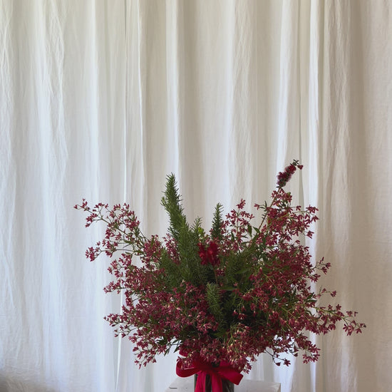 Festive red Christmas flower vase with seasonal blooms